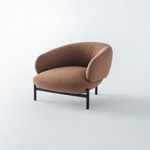 Freda armchair by HOMAGE KOLTUK with plush fabric upholstery and modern design, shown in a cozy living room setting.