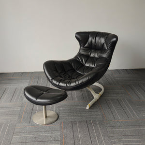 Black Vexel lounge chair with matching ottoman by BEACON, modern design, plush upholstery, and sleek legs perfect for relaxing spaces.