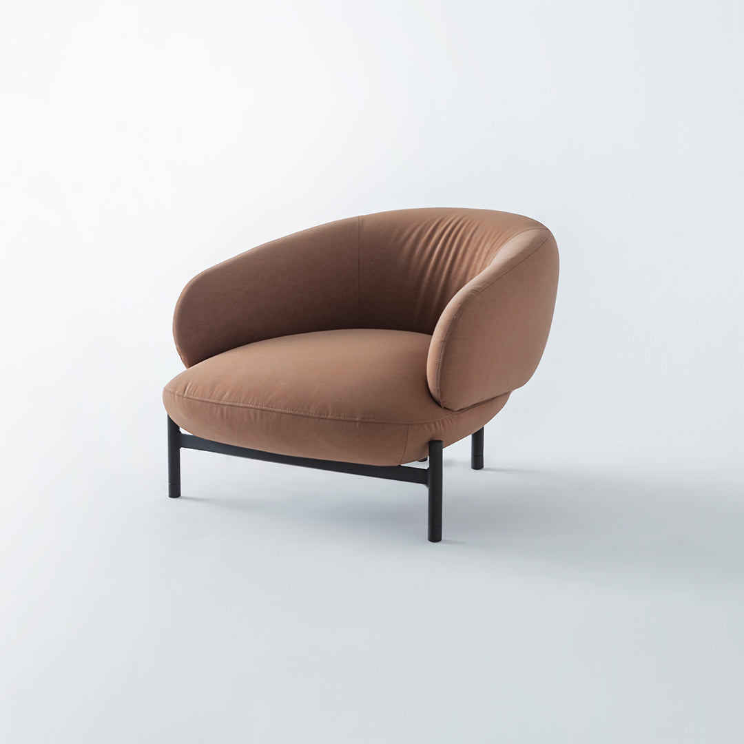 Freda armchair by HOMAGE KOLTUK with plush fabric upholstery and modern design, shown in a cozy living room setting.